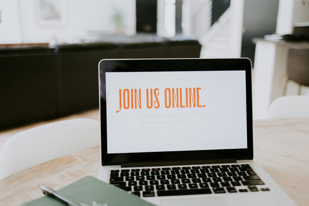 Laptop on table with "Join Us Online" written on the screen